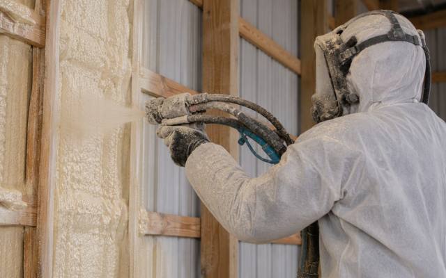 Installer spraying foam on the steel wall of a commercial building in Kitchener