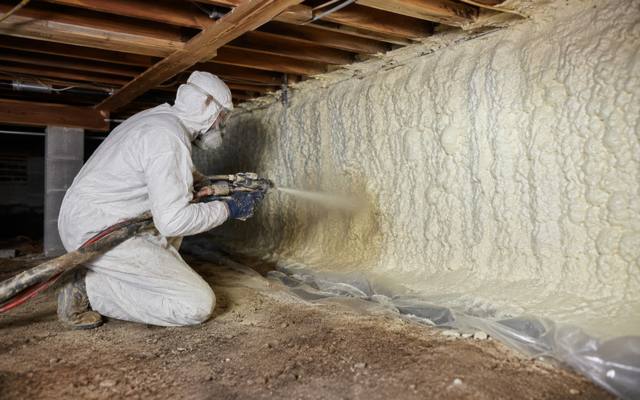Installer spraying foam on a crawl space wall in Kitchener